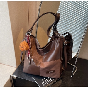 Detail view of coffee brown patchwork tote bag with teddy bear charm and mirror reflection