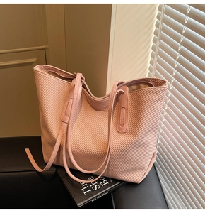 Detail of light pink tote bag with woven texture on black leather surface