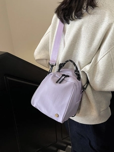 Light purple nylon shell backpack with woven handles and gold logo badge for women