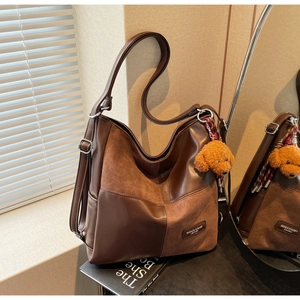 Close-up of retro brown patchwork tote bag with side pocket and cute dog charm pendant