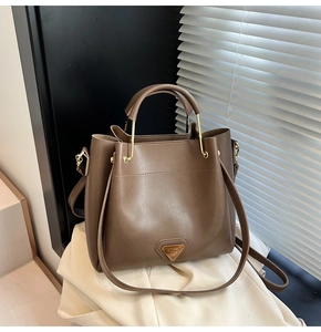 Détail du sac seau marron foncé montrant les ferrures dorées et le grain du cuir