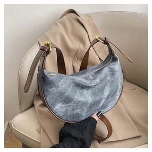 Detailed view of crescent dumpling bag in denim and brown leather with golden hardware