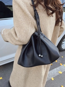 Retro black litchi leather bucket bag with drawstring and silver bead details on model