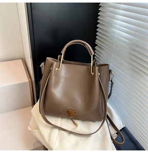 Vue détaillée d'un sac seau en cuir marron foncé avec un logo en métal triangulaire