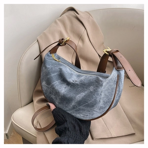 Detailed shot of retro blue denim crescent bag with premium brown leather strap