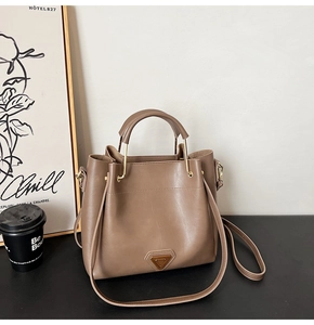 Détail du sac seau en similicuir marron avec un ornement en métal triangle doré