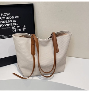 Detail of canvas tote bag with brown faux leather handles and reinforced stitching