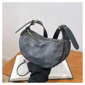 Detail of dark grey washed denim crescent bag featuring leather strap and gold metal hardware