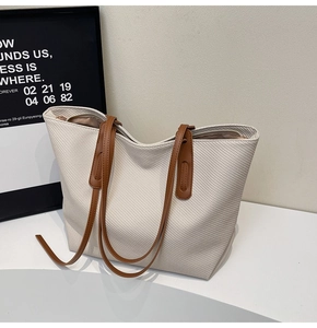 Detailed macro view of cream woven tote bag with brown leather handles and metal zipper