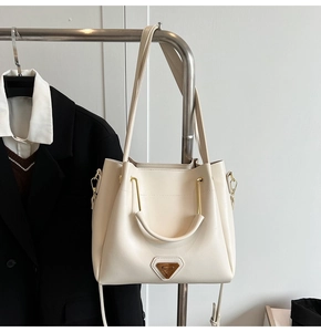 Gros plan du sac seau crème avec détail triangulaire suspendu à un cintre épuré