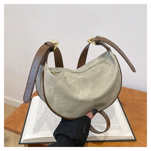 Close-up of crescent dumpling bag in beige canvas with brown leather trim and metal zipper