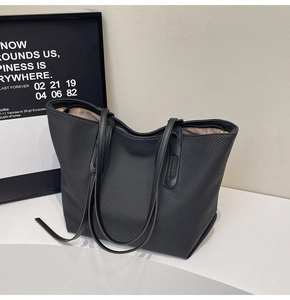 Detail of black woven tote bag with leather straps and spacious beige interior lining