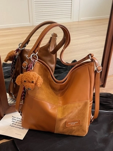 Vintage college-style caramel leather tote bag with plush dog charm and side zipper detail
