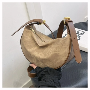 Detail of adjustable leather strap and golden metal buckle on brown crescent crossbody bag