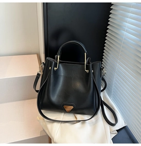 Détail du sac seau noir mat avec poignées métalliques en U et bandoulière réglable