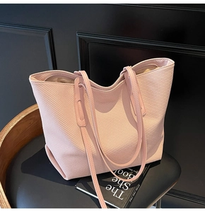 Detail of light pink woven tote bag with slim shoulder straps on a classic chair