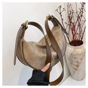 Close-up of vintage canvas crescent bag with leather strap and gold metal buckle detail