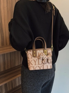 Schicke beige Beuteltasche mit braunem Besatz und LUCKY-Print von einem Model getragen