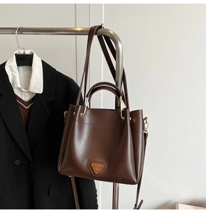 Détail d'un sac seau en cuir marron foncé avec ferrures dorées sur un présentoir