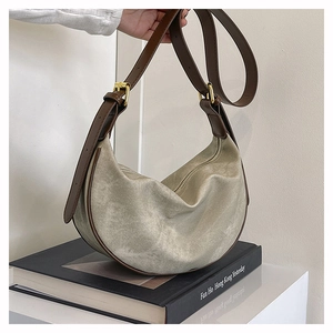 Detail of grey-green canvas crescent bag with dark brown leather strap and metal buckle