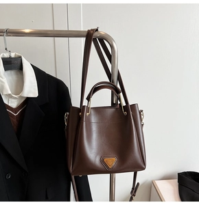 Détails du sac seau en cuir marron foncé avec plaque en métal doré et poignées de transport