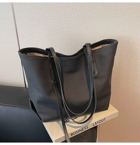 Detail shot of black tote bag with quilted texture and metal zipper closure on top