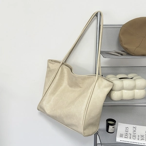 Bolso tote beige minimalista de cuero sintético mate colgado en un soporte moderno