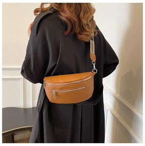 Detailed view of brown pebbled leather saddle bag with striped strap on model's back