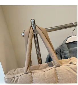 Close-up of durable padded handles on a beige quilted tote bag hanging on a rack