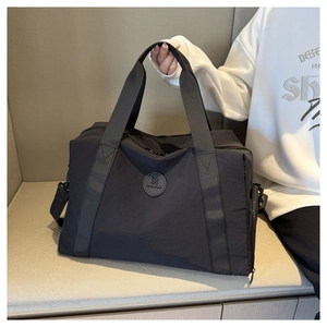 Close-up of black Oxford cloth travel bag with reinforced handles and brand logo detail