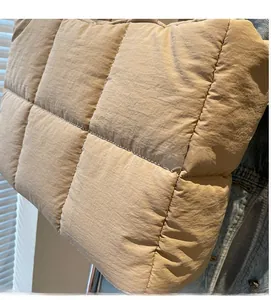 Detail of beige quilted down-style tote bag showing soft padded square texture