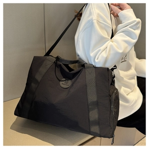 Detailed view of black nylon travel bag with brand patch and side zipper compartment