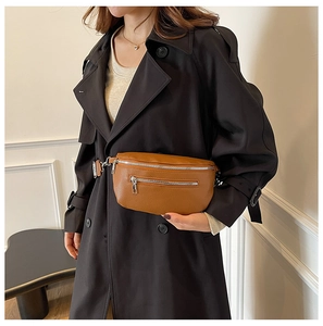 Detailed view of brown litchi grain leather saddle bag with silver zippers and strap