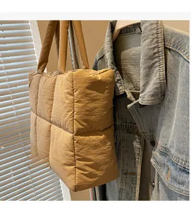 Close-up of khaki quilted tote bag featuring large square puffer stitching and long handles