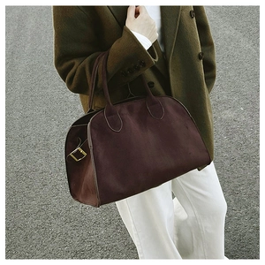 Close-up of deep burgundy tote bag with gold buckle detail shown in street style