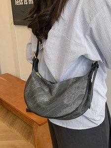 Retro grey crescent crossbody bag with gold hardware worn by a model in casual style