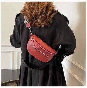 Detail of red pebbled leather saddle bag with striped woven strap on black coat