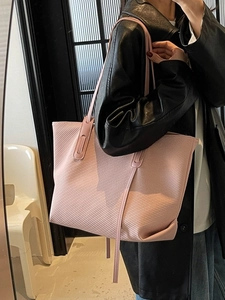 Pink textured leather tote bag with thin shoulder straps shown on a model