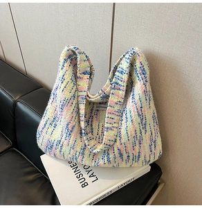 Detail einer mehrfarbigen Tweed-Einkaufstasche mit Innenetikett auf schwarzem Ledersofa