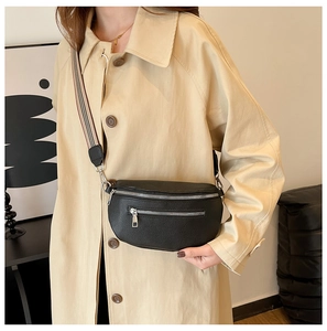 Detail of black lychee grain saddle bag with striped strap and silver zipper pockets
