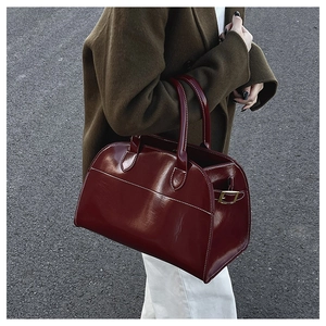 Close-up of wine red patent leather tote bag with white contrast stitching and gold buckle