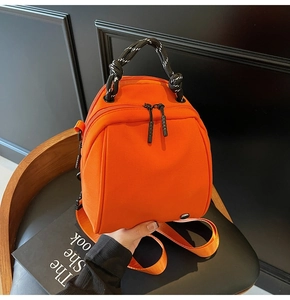 Detail van de feloranje mini-tas met een zwart-wit gevlochten touwhandvat