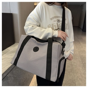 Close-up of light grey Oxford travel bag showing side zipper pocket and black logo