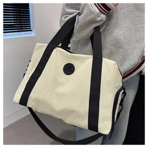 Detail of travel tote bag with black round logo patch and durable nylon webbing strap
