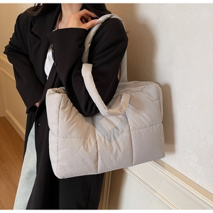 Macro detail of quilted puffer tote bag in grey showing stitching and soft texture
