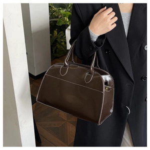 Detail of dark brown glossy tote bag with white contrast stitching and gold buckles