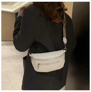 Close-up of white lychee pattern leather saddle bag with silver zippers and nylon strap