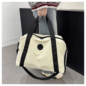 Close-up of beige travel bag showing sturdy black handles and leather logo detail
