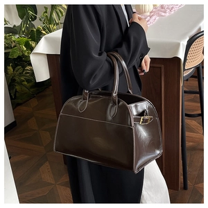 Detail of deep brown tote bag with contrast stitching and golden metal buckle