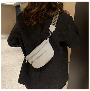 Detailed back view of white lychee leather saddle bag with striped woven strap and zippers